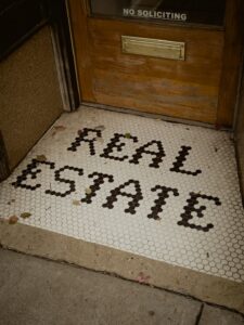 A real estate agent explaining paperwork to a couple during a home viewing inside a bright residential living room.