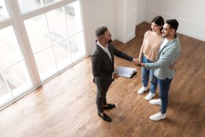 Buyers inspect a home’s kitchen and HVAC vents while taking notes during a real estate showing.